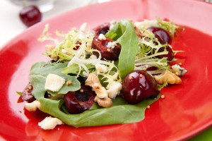 Green salad with sweet cherries, candied pistachios and goat cheese rounds